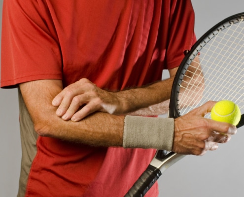 tennis player massaging elbow - Colorado Center of Orthopaedic Excellence tennis elbow