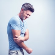 People, healthcare and problem concept - close up of man suffering from pain in hand or elbow - Colorado Center of Orthopaedic Excellence bicep tendonitis