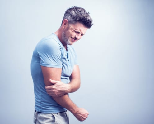People, healthcare and problem concept - close up of man suffering from pain in hand or elbow - Colorado Center of Orthopaedic Excellence bicep tendonitis