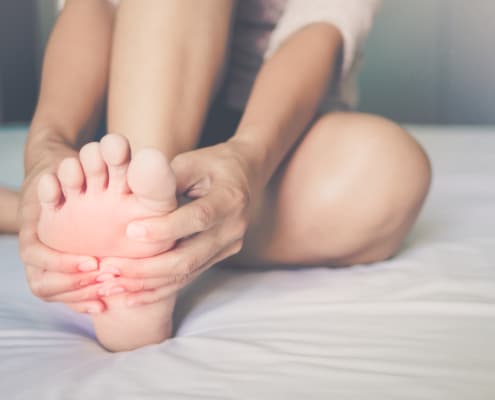 health care concept. woman massaging her painful foot, red hi-lighted on pain area - Colorado Center of Orthopaedic Excellence Podiatry